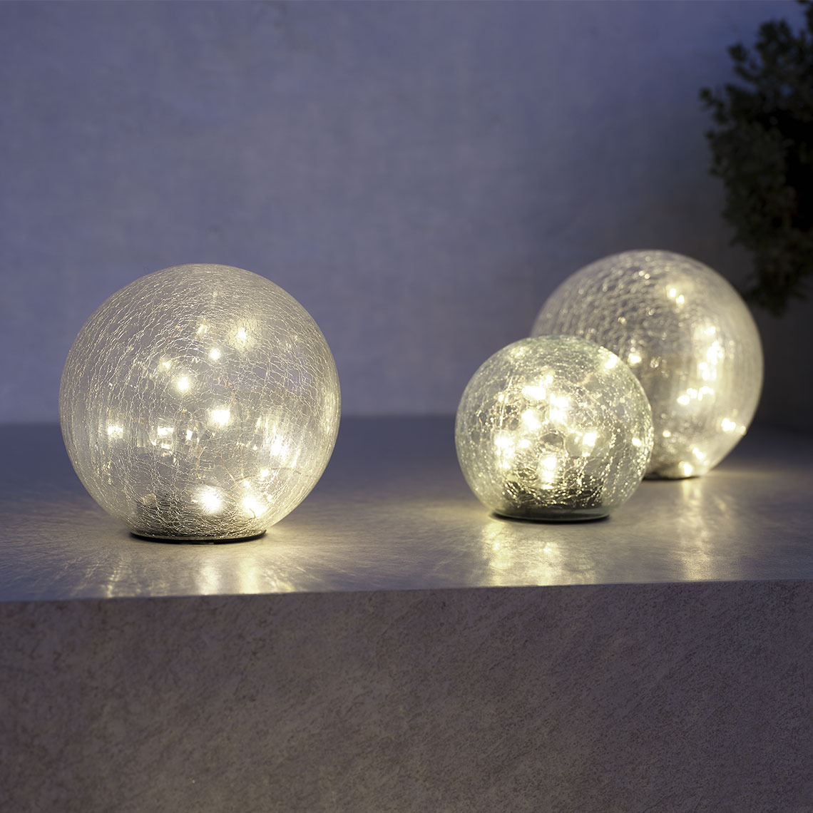 HAVSVALE solcellelamper Tre runde solcellelamper på en terrasse, der lyser op i mørket